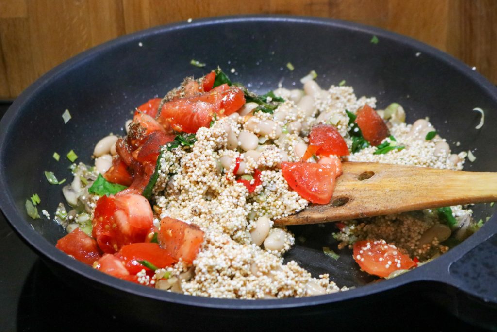 quinoa, tomatoes, seasoning in skillet, cooking.