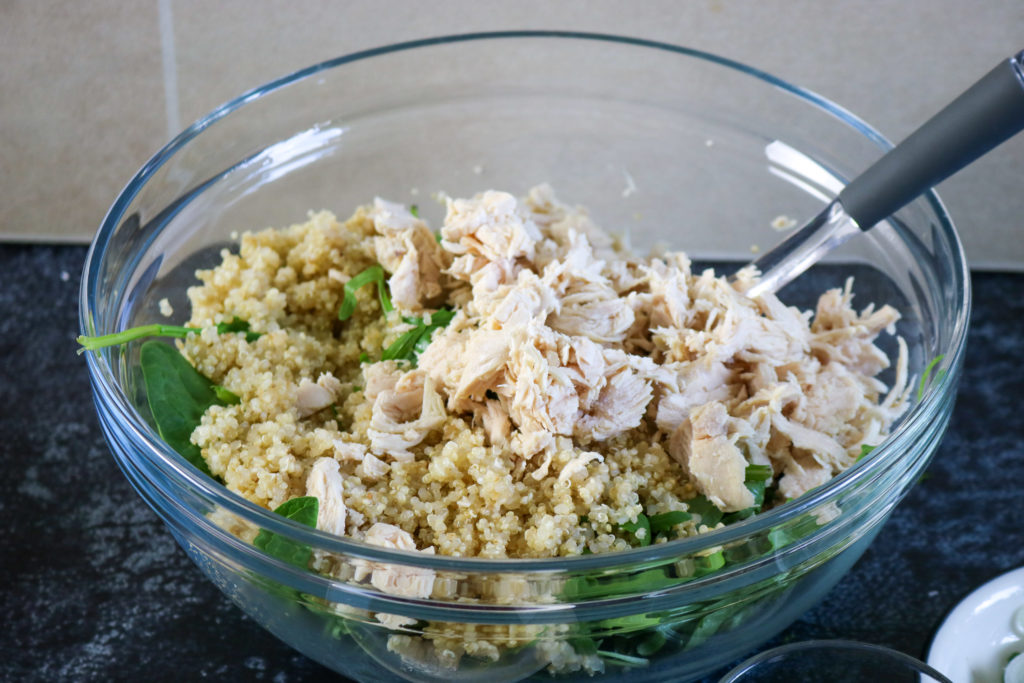 chicken, quinoa and arugula in bowl with spoon